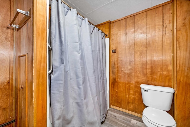 bathroom with hardwood / wood-style flooring, wooden walls, and toilet