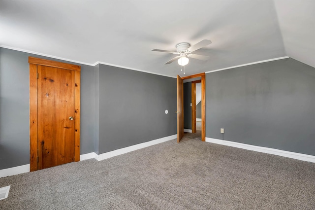 carpeted empty room with vaulted ceiling, ornamental molding, and ceiling fan