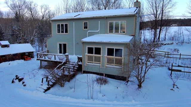 snow covered house featuring a wooden deck