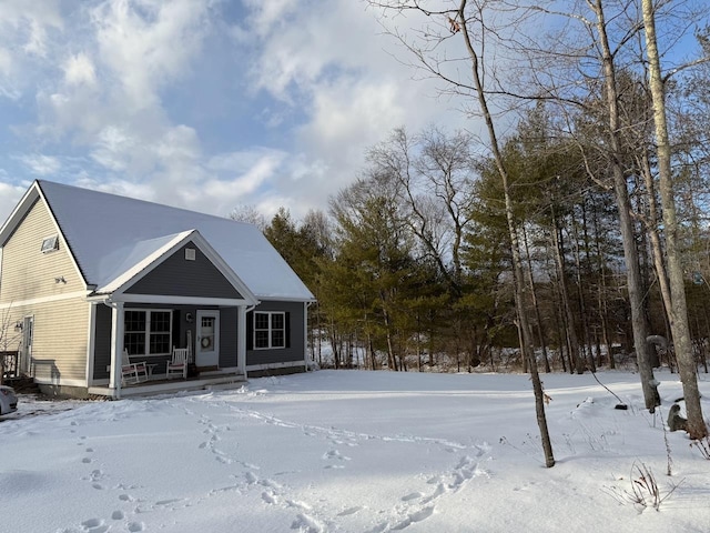 snow covered back of property featuring a porch