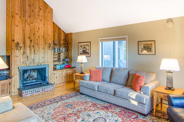 living room featuring lofted ceiling, wood-type flooring, a brick fireplace, baseboard heating, and wooden walls