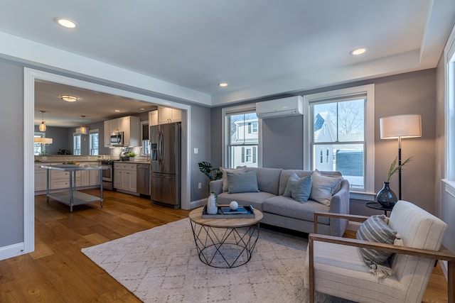 living room with wood-type flooring and an AC wall unit