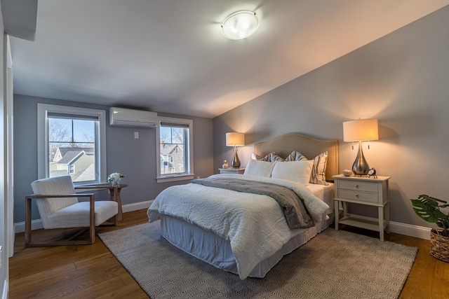 bedroom featuring hardwood / wood-style flooring, vaulted ceiling, and a wall unit AC