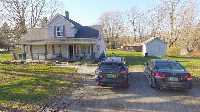 view of front of home with a shed, a front yard, and a porch