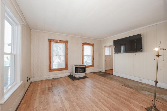 unfurnished living room featuring crown molding, a wood stove, and light hardwood / wood-style flooring