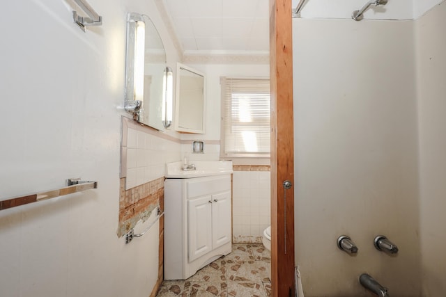 bathroom with vanity, tile walls, and toilet