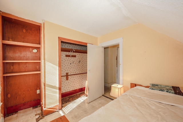 bedroom featuring vaulted ceiling, a closet, and a textured ceiling