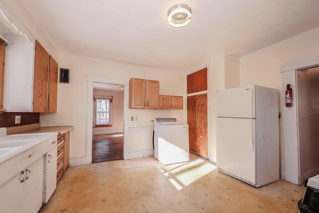 kitchen with washer / clothes dryer, crown molding, and white refrigerator