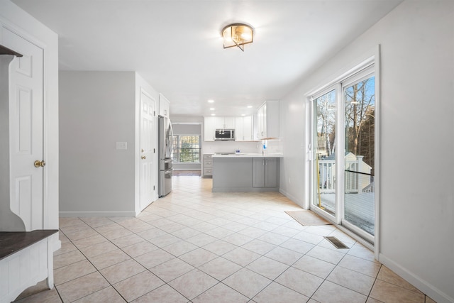 kitchen with stainless steel appliances, white cabinetry, and light tile patterned floors