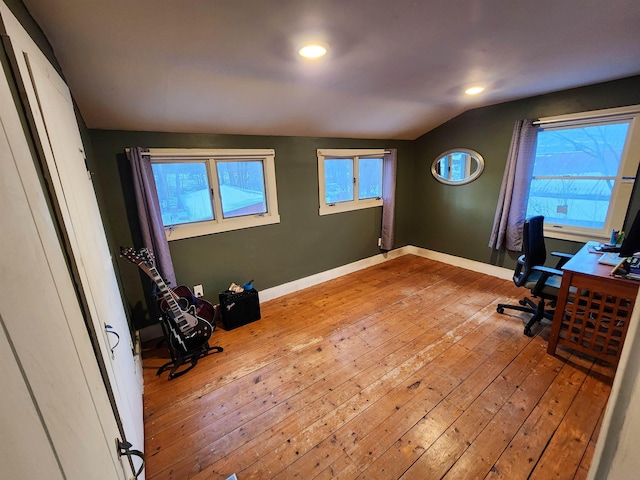 office space featuring lofted ceiling, a healthy amount of sunlight, and light hardwood / wood-style flooring