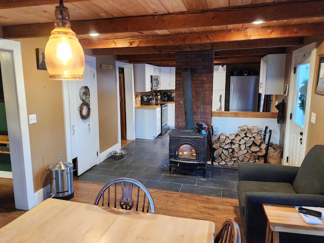 dining space with beamed ceiling, wooden ceiling, and a wood stove