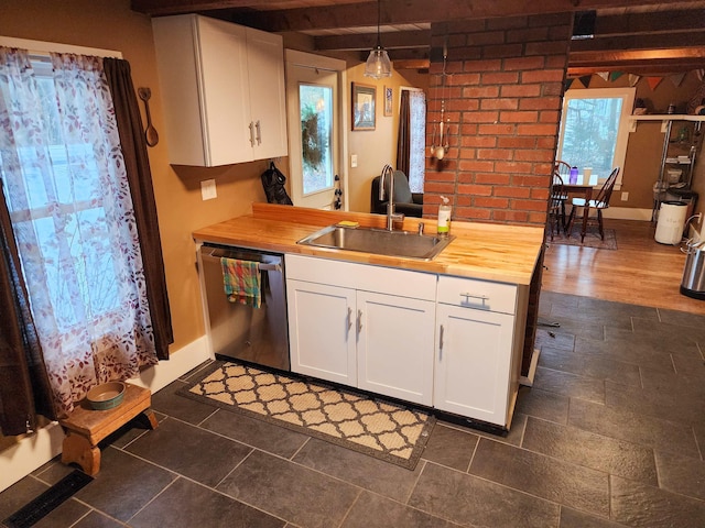 kitchen featuring butcher block counters, hanging light fixtures, sink, and dishwasher