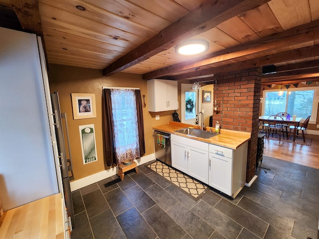 kitchen featuring wood counters, white cabinetry, sink, dishwashing machine, and hanging light fixtures