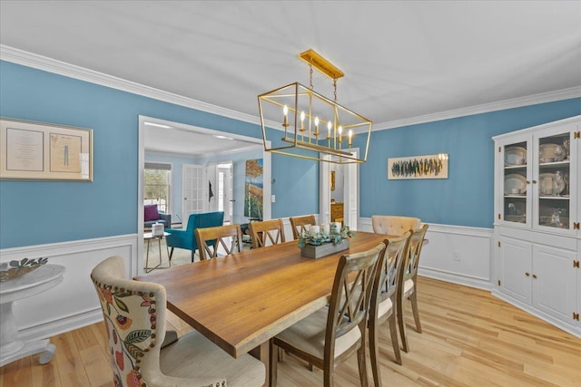 dining room with crown molding, an inviting chandelier, and light wood-type flooring