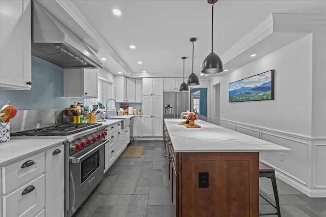 kitchen featuring white cabinetry, light stone counters, premium appliances, a kitchen island, and wall chimney exhaust hood