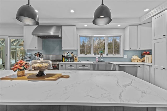 kitchen with wall chimney range hood, hanging light fixtures, sink, and dishwasher