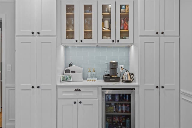 bar featuring backsplash, beverage cooler, and white cabinets