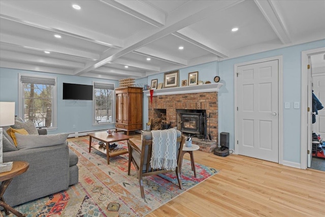 living room with coffered ceiling, beam ceiling, a wood stove, and light wood-type flooring