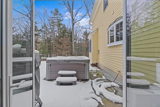 view of snow covered exterior with a hot tub