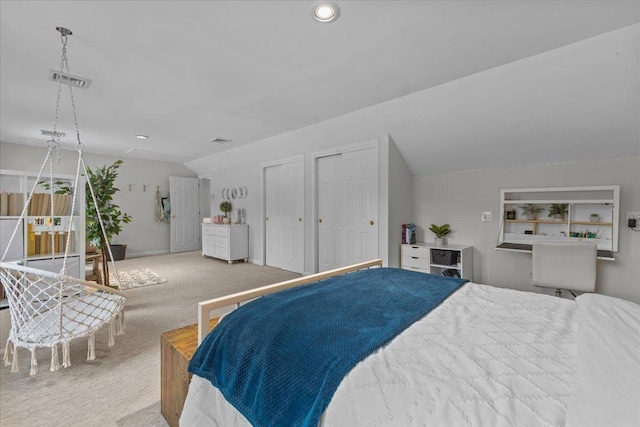 carpeted bedroom featuring vaulted ceiling and multiple closets