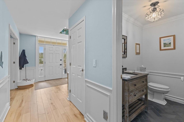 foyer featuring an inviting chandelier, crown molding, and light hardwood / wood-style floors