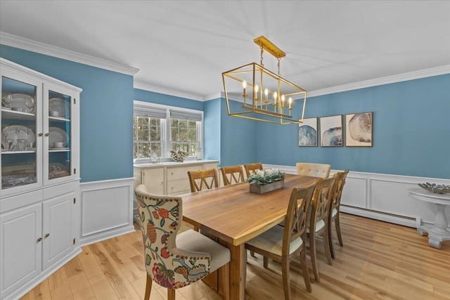 dining room featuring an inviting chandelier, ornamental molding, light hardwood / wood-style flooring, and a baseboard heating unit