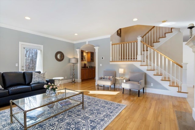 living room with decorative columns, ornamental molding, and wood-type flooring