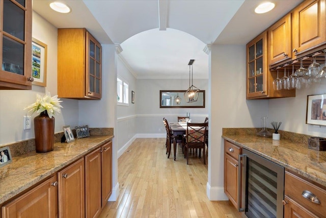 bar featuring stone countertops, wine cooler, hanging light fixtures, crown molding, and light wood-type flooring