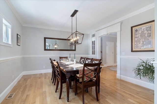 dining space with crown molding, light hardwood / wood-style floors, and a notable chandelier