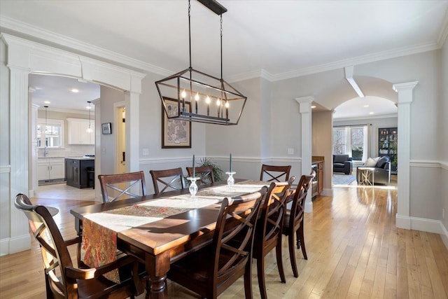 dining area with ornamental molding, light hardwood / wood-style flooring, and ornate columns