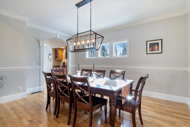 dining space with an inviting chandelier, crown molding, light hardwood / wood-style flooring, and ornate columns