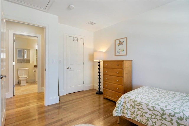 bedroom featuring ensuite bath, light hardwood / wood-style flooring, and a closet