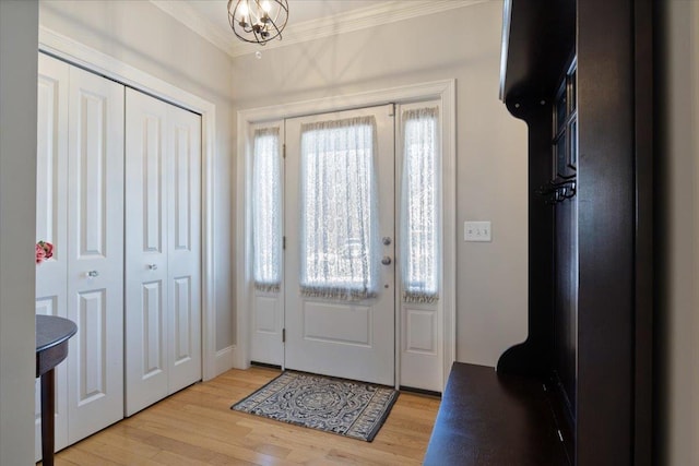 foyer entrance featuring a notable chandelier, crown molding, and light wood-type flooring