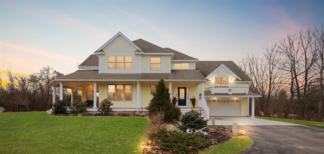 view of front facade with a garage, covered porch, and a lawn