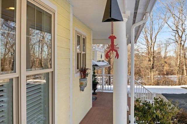 snow covered back of property featuring a porch