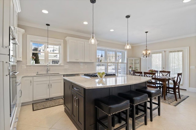 kitchen featuring light stone counters, sink, a kitchen island, and white cabinets