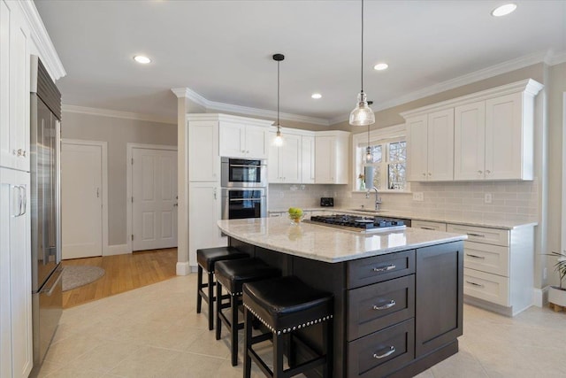 kitchen with pendant lighting, crown molding, appliances with stainless steel finishes, a center island, and white cabinets