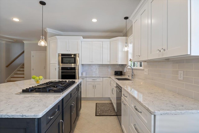 kitchen with sink, appliances with stainless steel finishes, white cabinets, a kitchen island, and decorative light fixtures