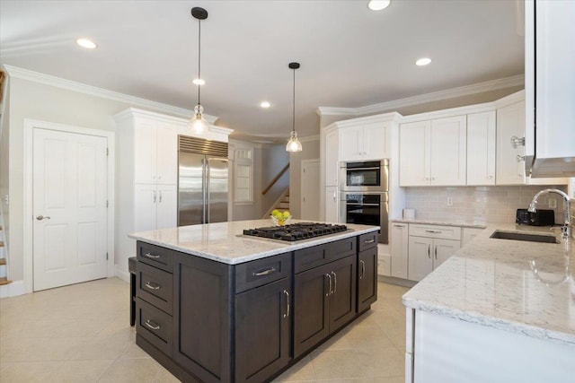 kitchen with pendant lighting, sink, white cabinetry, stainless steel appliances, and a center island