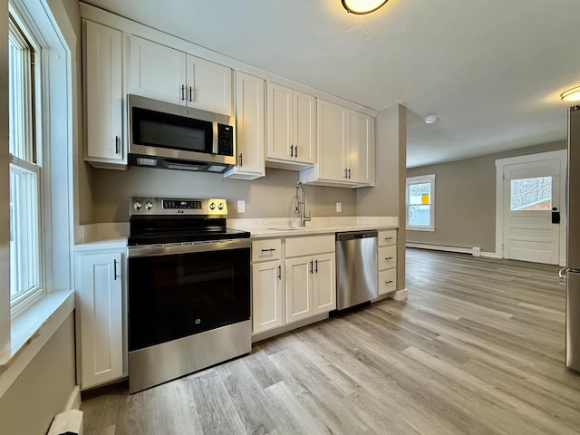 kitchen with a baseboard heating unit, stainless steel appliances, and white cabinets