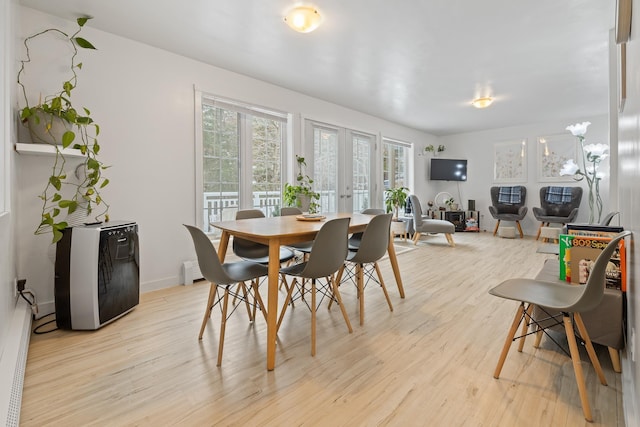 dining space featuring a baseboard radiator, light hardwood / wood-style floors, and french doors