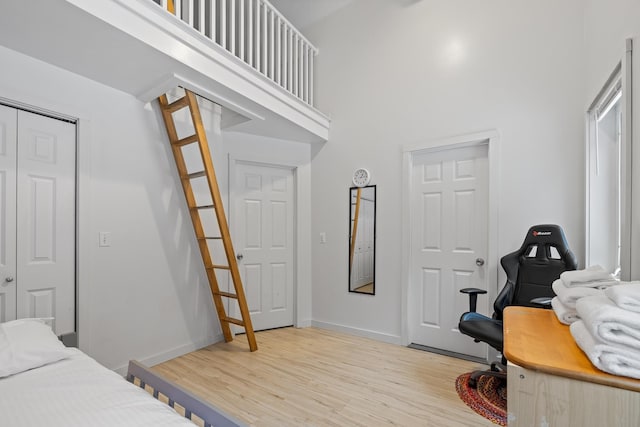 bedroom with light hardwood / wood-style floors, a closet, and a high ceiling