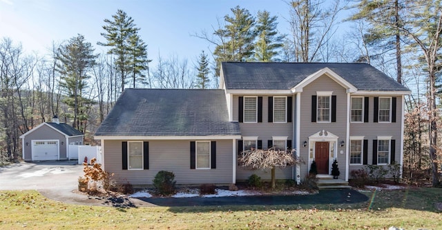 colonial-style house featuring a garage, an outdoor structure, and a front yard