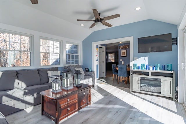 living room featuring ceiling fan, vaulted ceiling, and light wood-type flooring