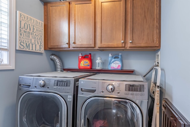 clothes washing area featuring cabinets and washing machine and clothes dryer