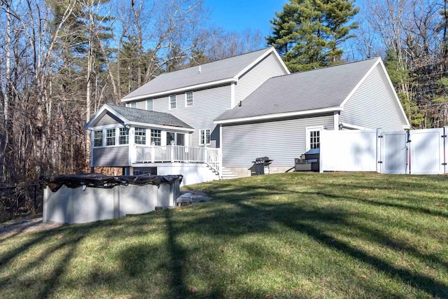 rear view of property with a yard and a swimming pool side deck