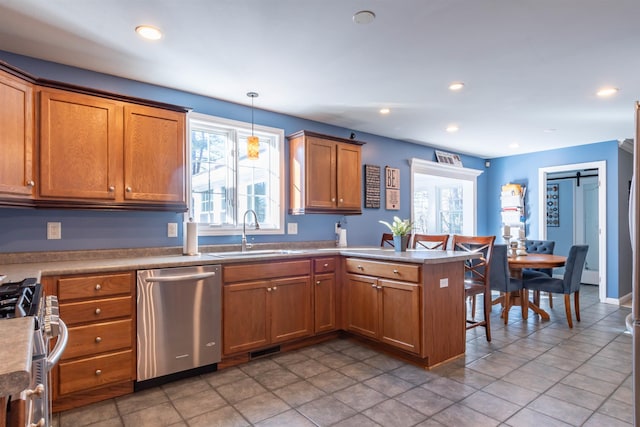 kitchen with pendant lighting, sink, appliances with stainless steel finishes, plenty of natural light, and kitchen peninsula