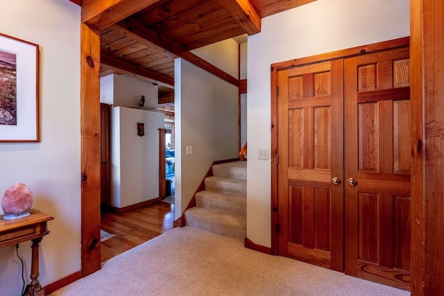 corridor featuring light carpet, wooden ceiling, and beam ceiling