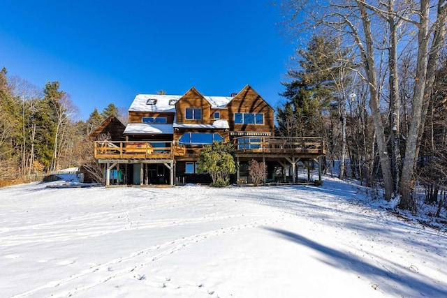 snow covered rear of property with a wooden deck