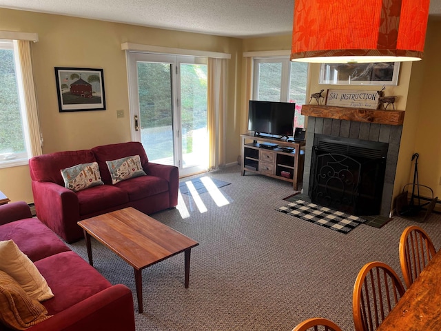 carpeted living room featuring a baseboard heating unit, a wealth of natural light, a fireplace, and a textured ceiling